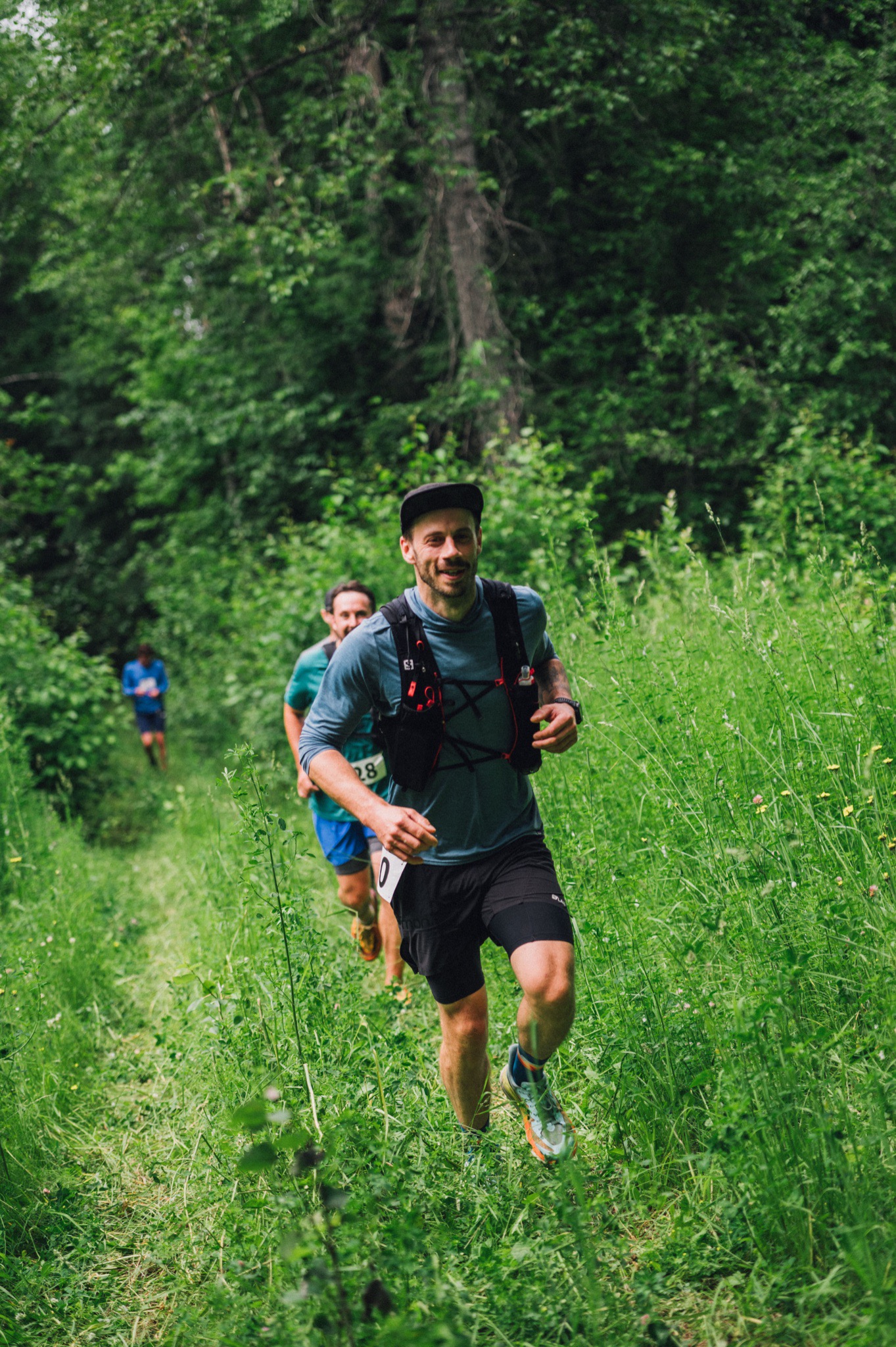 Runners climbing a lush green trail